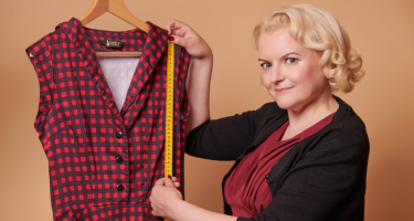 Eine Frau hält ein Maßband an ein Kleid